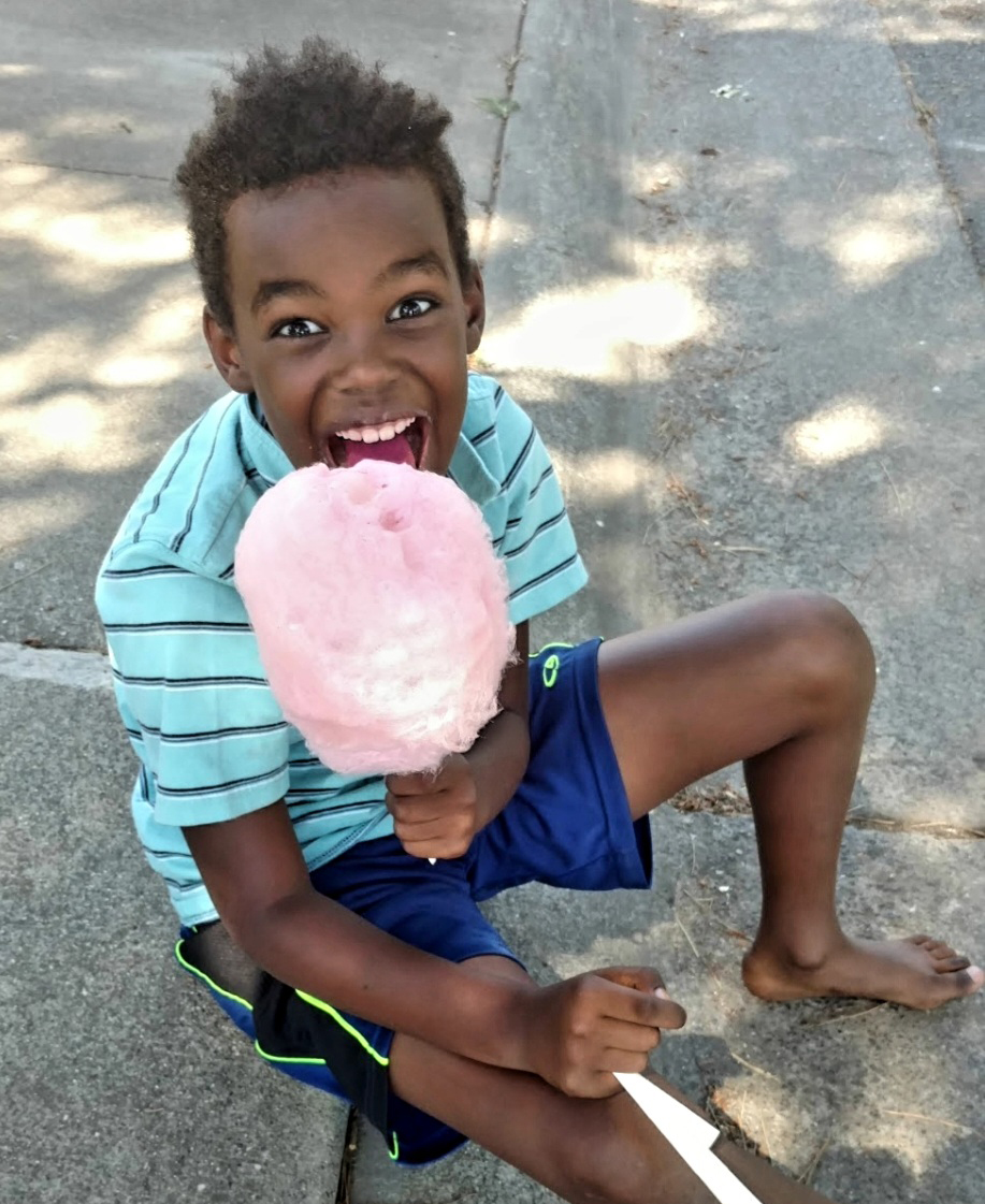 child with excited expression holding cotton candy